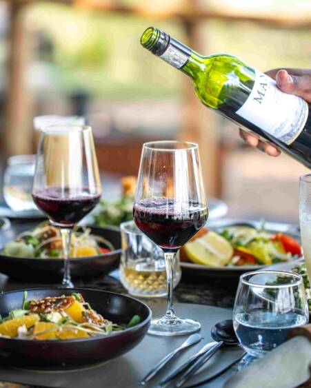 Wine being poured surrounded by plates of food